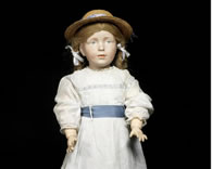 The World's Most Expensive Doll sold at auction wears a white dress with lace sleeves and a powder blue ribbon sash which matches her finely painted blue-grey eyes. A delicate straw hat sits on top of her auburn, plaited hair. This doll has unique pierced ears and a more adult expression than the other dolls, capturing a striking portrait of a young lady. No other example of this doll is known. It is therefore possible that she was an experimental mold. 
